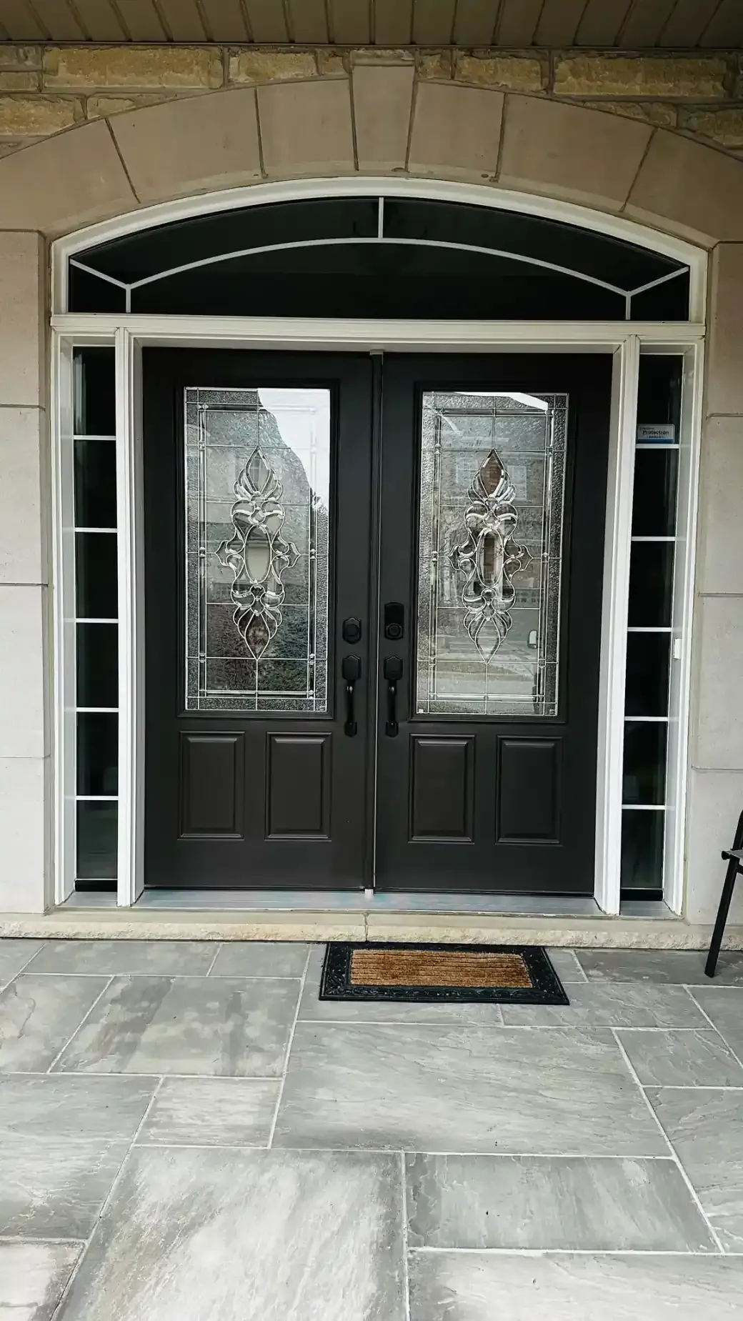 Double entry doors with decorative glass and sidelights on a stone home in Vaughan, Ontario